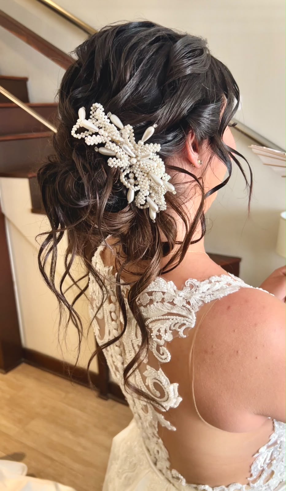 Bride with a side-swept bun finished with a floral and pearl hair piece