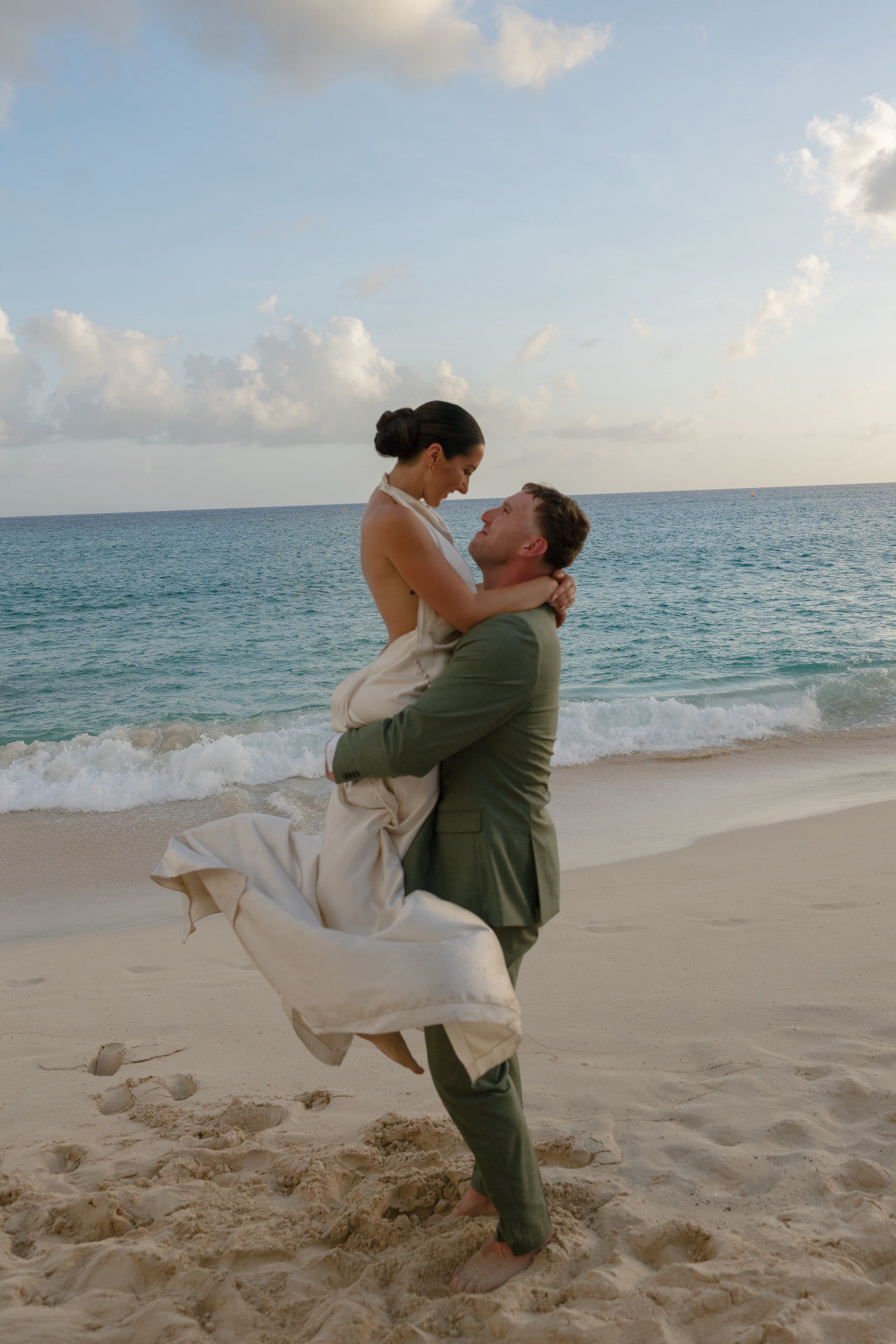 Groom lifting his bride on a Caribbean beach at sunset